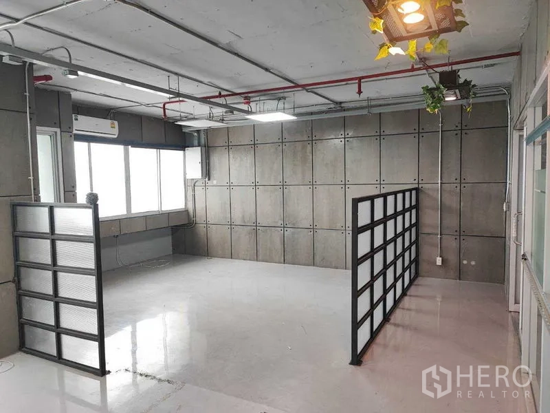 Office Space for rent in Watthana, Bangkok - Workspace corner with two semi-transparent partitions, concrete feature wall and hanging planter light.