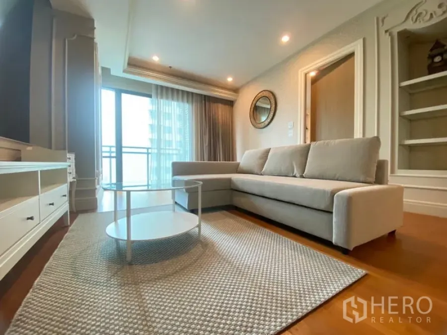 Condominium for rent in Khlong Toei, Bangkok - Bright living area with L-shaped sofa, floor-to-ceiling window and balcony access in a Khlong Toei condo.