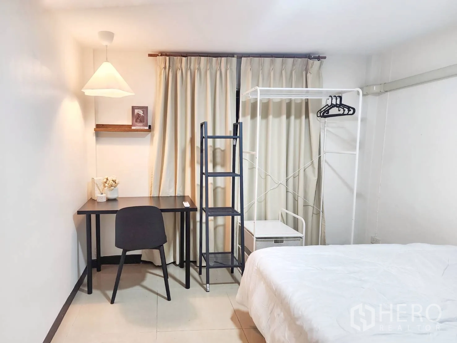 Detached House for rent in Huai Khwang, Bangkok - Bedroom with desk, shelving unit, clothes rail, and soft lighting by curtains.