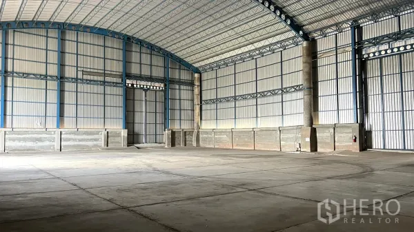 Warehouse for rent in Ban Pho, Chachoengsao - Spacious warehouse interior with high arched roof, steel trusses and smooth concrete floor.