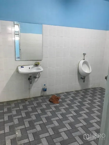 Warehouse for rent in Khlong Luang, Pathum Thani - Clean restroom with tiled walls and floor, wall-mounted sink and urinal.
