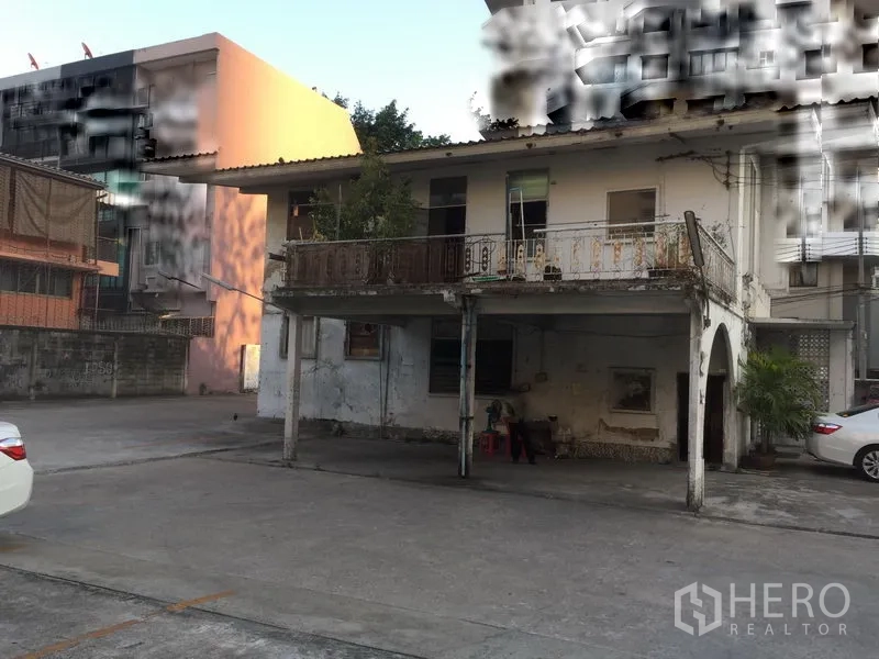 Retail Space for rent in Khlong Toei, Bangkok - Front view of an older two-storey house with balcony and covered carport facing a wide concrete yard.