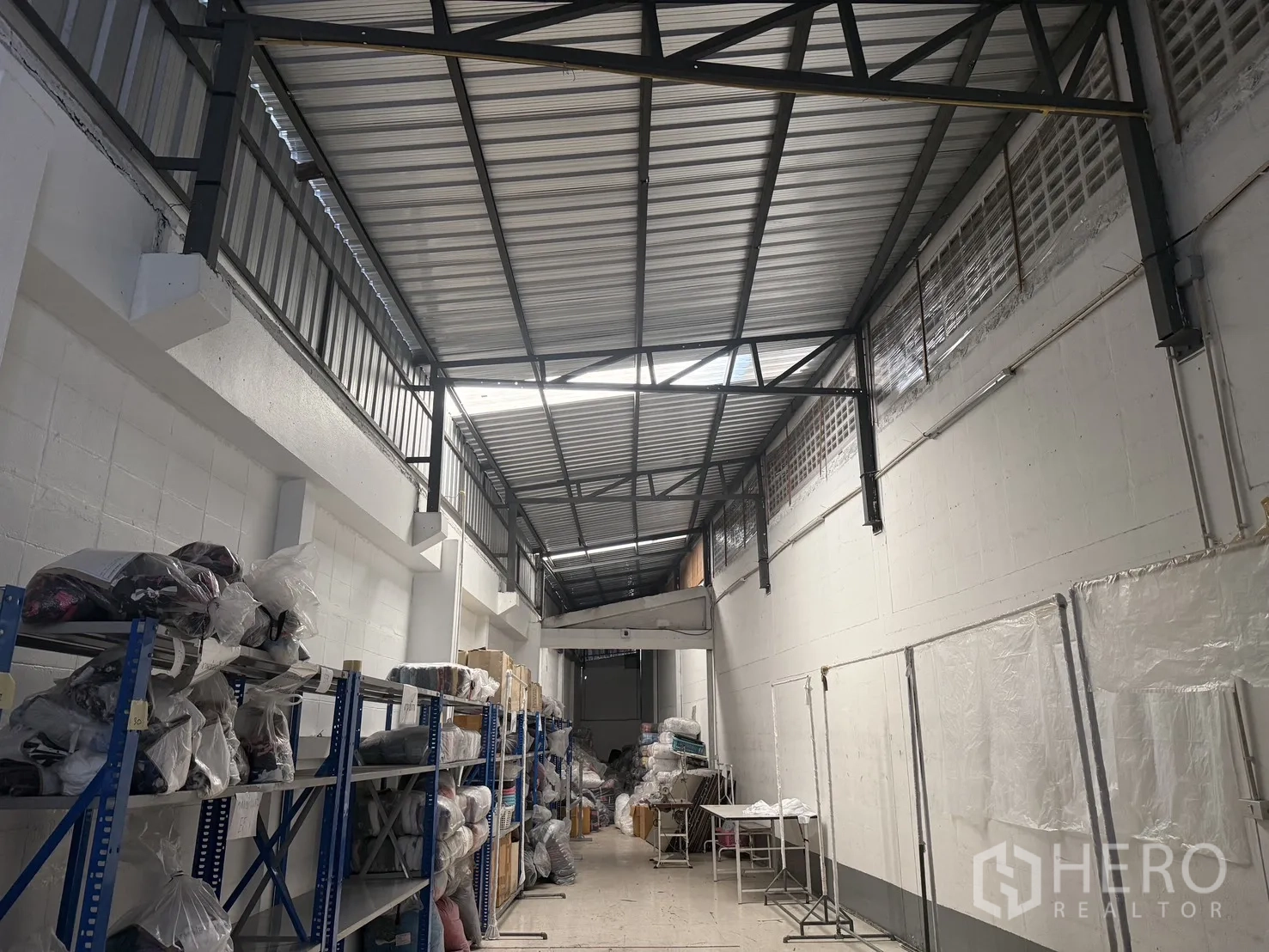 仓库 for rent in Suan Luang, Bangkok - 仓库内部设金属桁架高屋顶、砌块墙、钢制货架与宽敞通道。