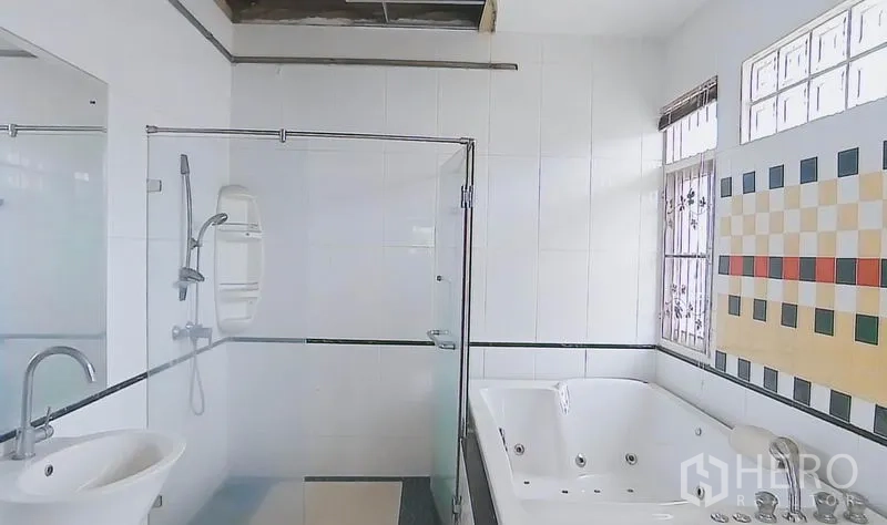 Detached House for sale in Bang Kapi, Bangkok - Bright bathroom with glass shower, jetted bathtub, tiled walls and a window.