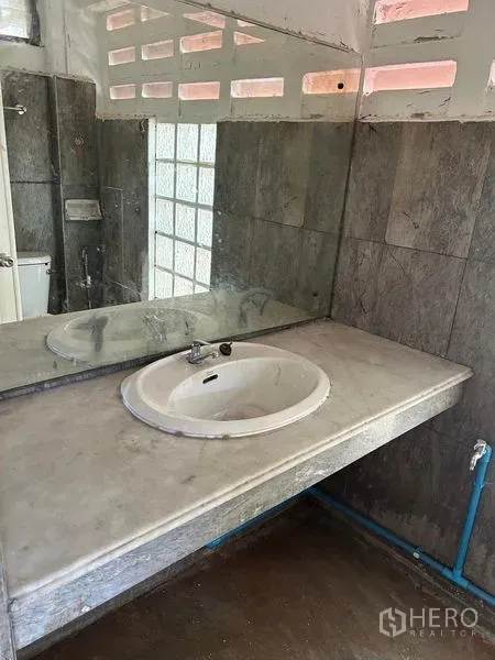 Warehouse for rent in Mueang Samut Prakan, Samut Prakan - Industrial restroom with a stone countertop sink and large wall mirror.