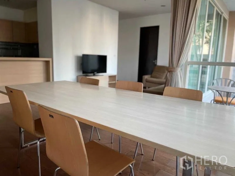 Condominium for rent in Pathum Wan, Bangkok - Dining space with six chairs facing TV corner and sliding glass doors to a balcony.