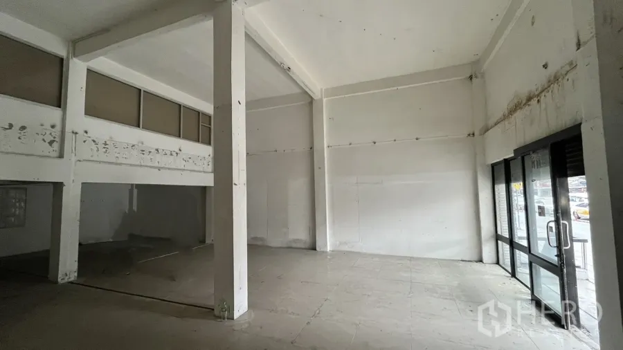 Shophouse for rent in Watthana, Bangkok - Double-height shophouse ground floor with glass storefront doors and tiled floor.
