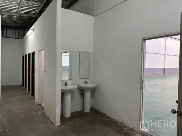 工厂 出租或出售在Bang Phli, Samut Prakan - 厂内洗手区与多间卫生间，旁侧为通往仓库的门。
