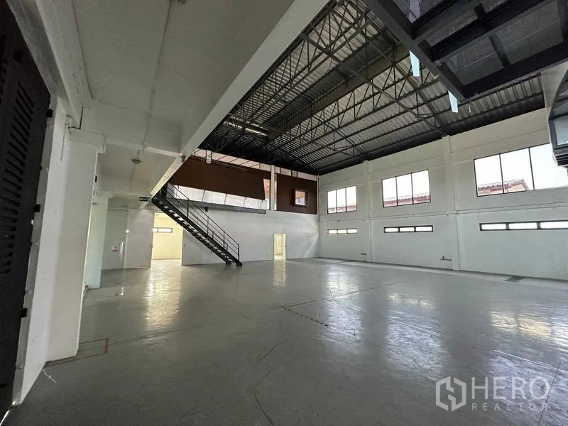 Warehouse for rent in Phra Khanong, Bangkok - Bright warehouse space with long clerestory windows and a glass entry door.