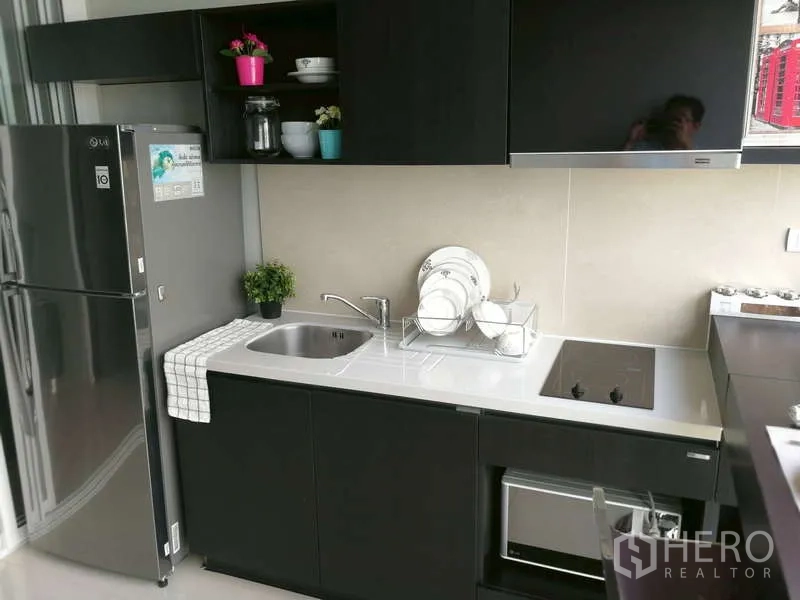 Condominium for sale - Sleek compact kitchen with induction hob, stainless sink, dish rack, microwave and full-size refrigerator.
