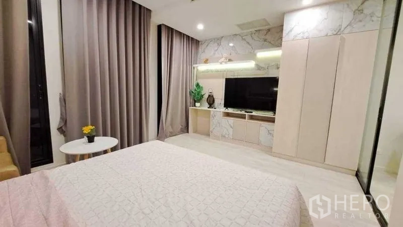 Condominium for rent or sale in Pathum Wan, Bangkok - Bedroom feature wall with marble accents, large TV, and floor-to-ceiling curtains.