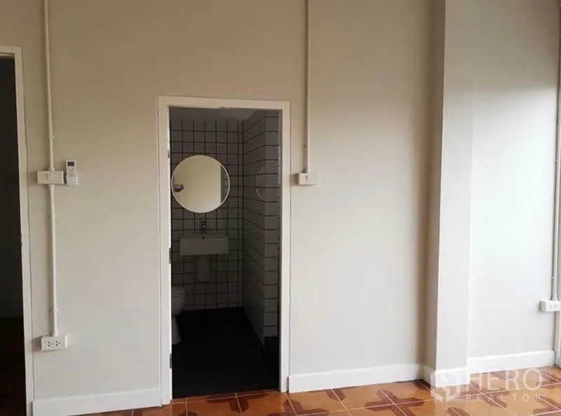Townhouse for rent or sale in Din Daeng, Bangkok - Ensuite bathroom entrance from the bedroom with tiled walls and a round mirror.