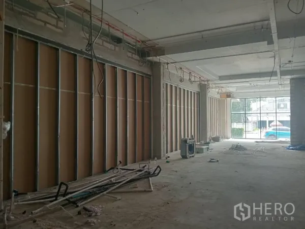 Retail Space for rent - View toward glass storefront and street from unfinished retail space with exposed wiring.