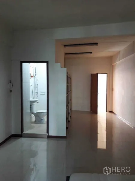 Shophouse for rent in Suan Luang, Bangkok - Corridor with bathroom featuring shower and toilet, built-in shelves and polished tile flooring.