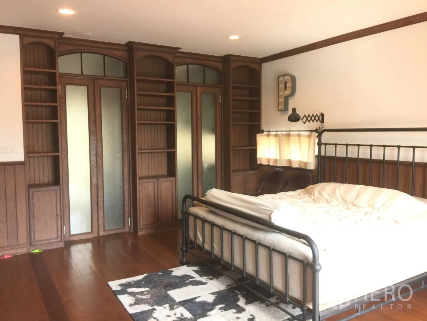 Townhouse for sale in Suan Luang, Bangkok - Spacious bedroom with iron bed, wooden floors, and built-in wardrobes.