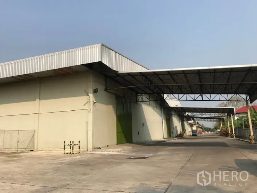 Warehouse for rent in Bang Pa-in, Phra Nakhon Si Ayutthaya - Front façade of warehouse featuring multiple green roll-up doors, canopy links, and straight truck access lane.