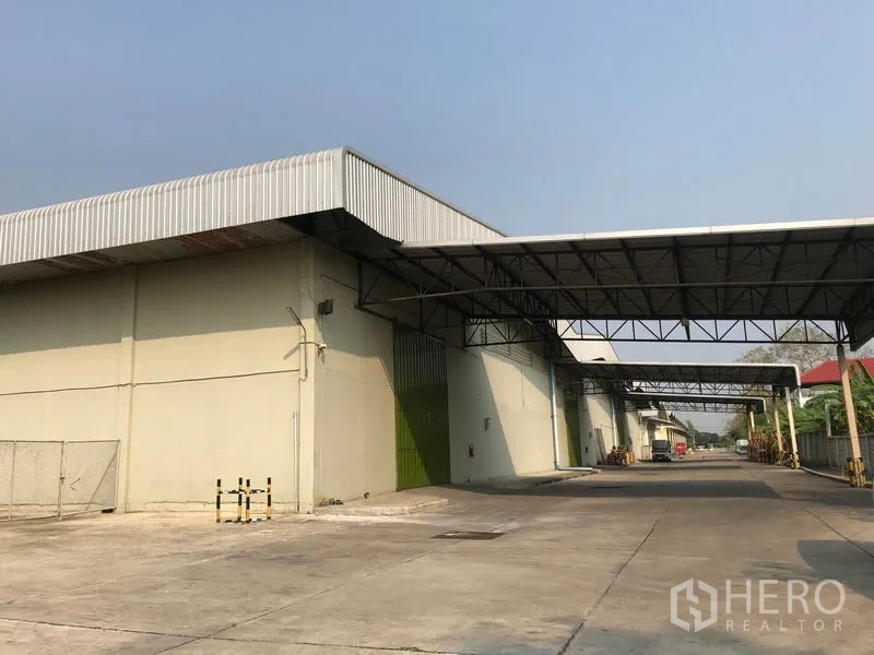 Warehouse for rent in Bang Pa-in, Phra Nakhon Si Ayutthaya - Front façade of warehouse featuring multiple green roll-up doors, canopy links, and straight truck access lane.
