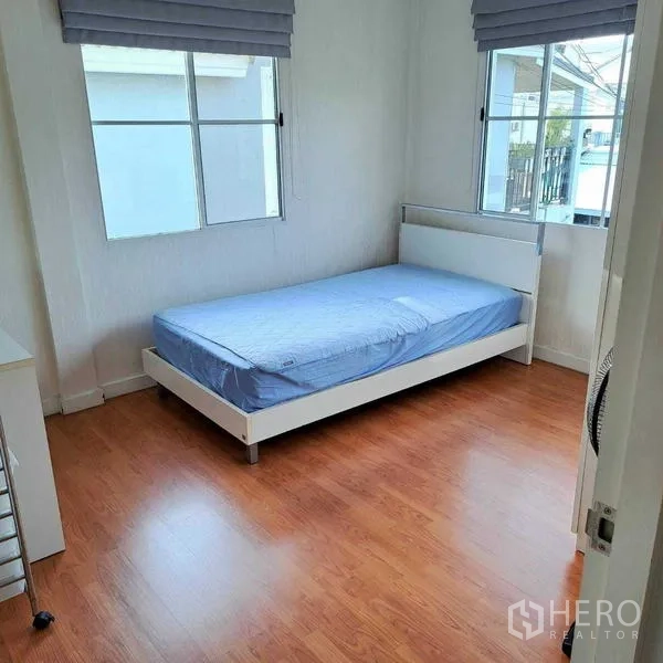 Detached House for rent in Prawet, Bangkok - Bright bedroom with a single bed, wood laminate flooring and two windows with blinds.