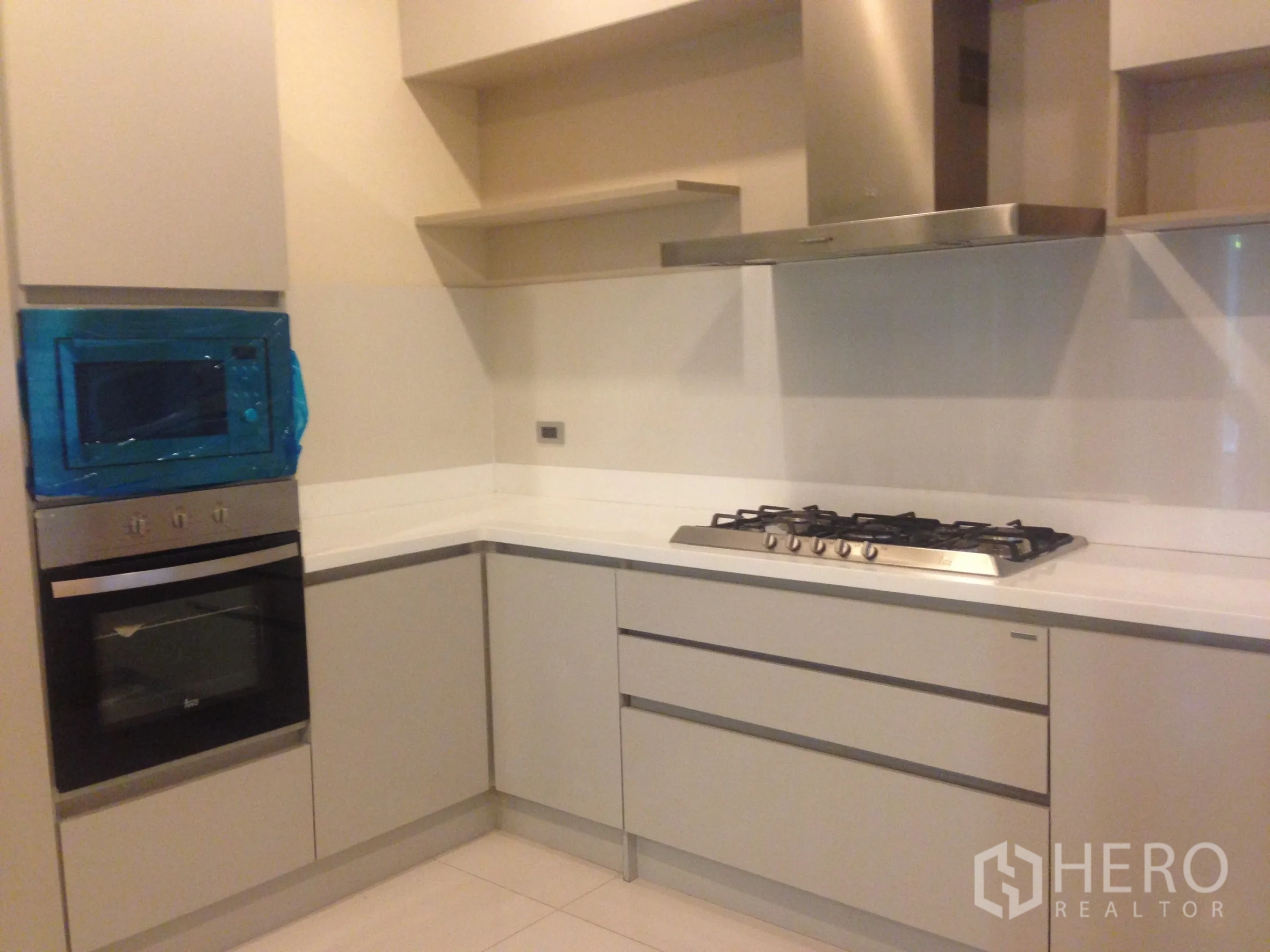 Townhouse for rent in Bang Kapi, Bangkok - Contemporary kitchen with built-in oven, gas cooktop and stainless-steel range hood.