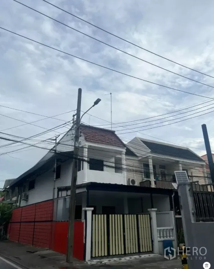 Townhouse for sale in Phra Khanong, Bangkok - Two-storey townhouse exterior in Bang Chak, Phra Khanong with gated carport and tiled roof.