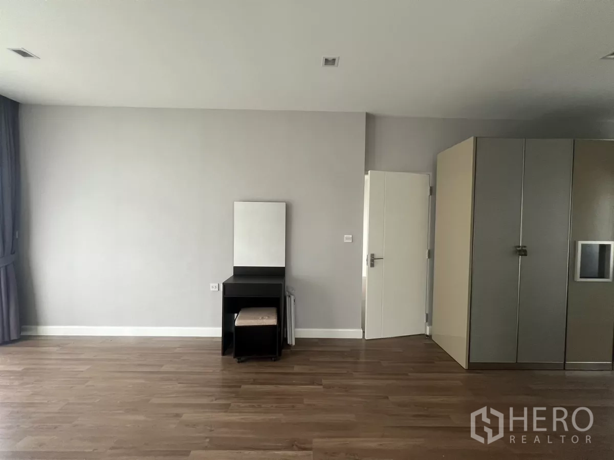 Detached House for sale in Bang Kapi, Bangkok - Bedroom corner with wardrobe storage, wood flooring, and white interior door.