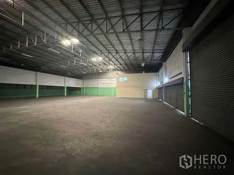โรงงาน ให้เช่าในNonthaburi - คลังสินค้าพื้นที่กว้าง เพดานโครงเหล็กสูง พื้นคอนกรีต และประตูม้วนหลายบาน.