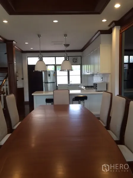 Detached House for rent in Khlong Toei, Bangkok - Dining room facing the kitchen island and stainless fridge under recessed lighting.