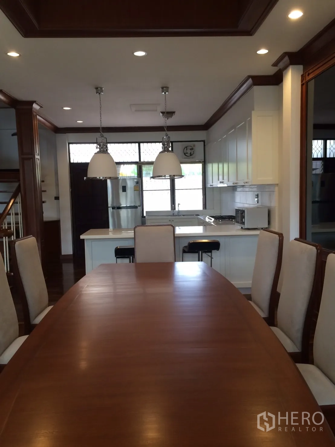 Detached House for rent in Khlong Toei, Bangkok - Dining room facing the kitchen island and stainless fridge under recessed lighting.