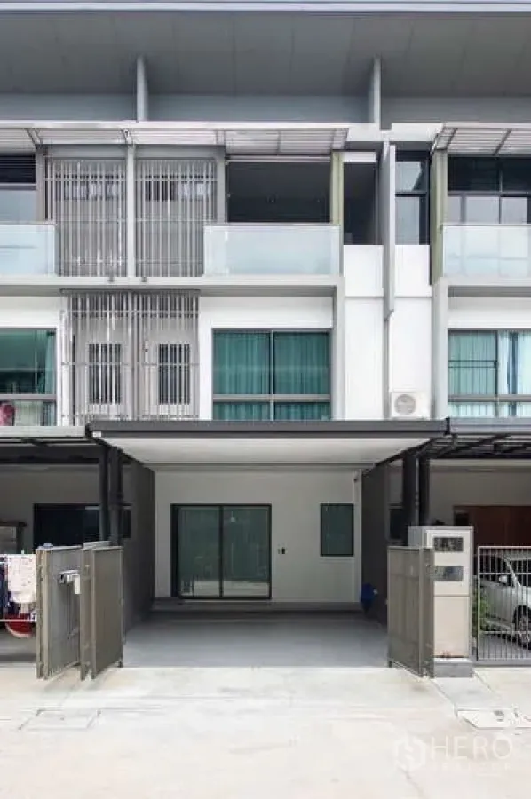 Townhouse for rent or sale in Lat Phrao, Bangkok - Three‑storey modern townhouse facade with balconies and gated entrance.