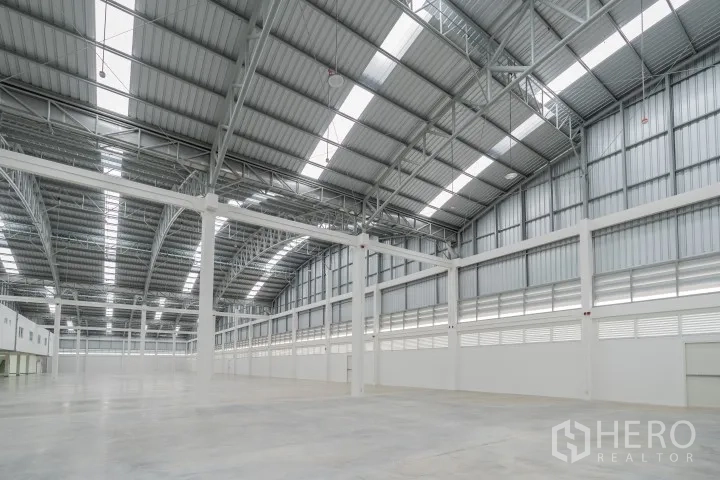 Factory for rent in Khlong Luang, Pathum Thani - Expansive open production space under an arched roof with rows of skylights and concrete floor.