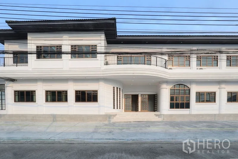 Office Space for rent in Bang Na, Bangkok - Two‑storey office facade with balcony, grid windows and a covered entry along a wide street in Bang Na.