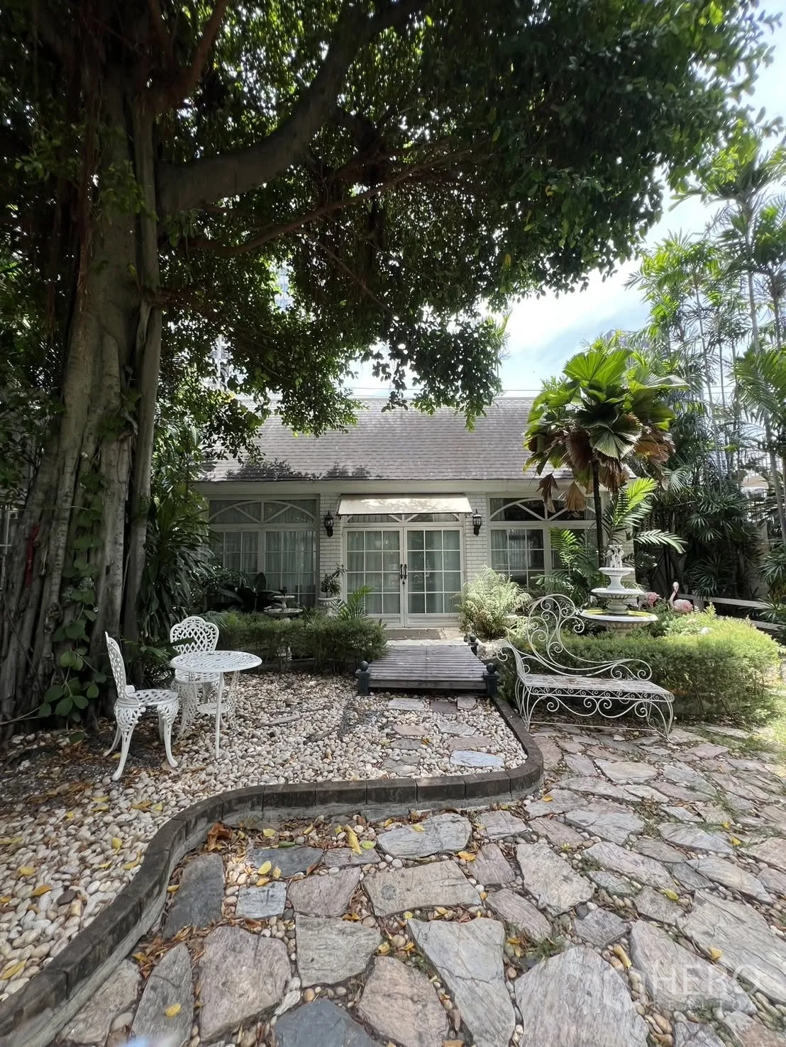 独栋房屋 for rent in Phra Khanong, Bangkok - 前庭大树、卵石步道与户外座椅。
