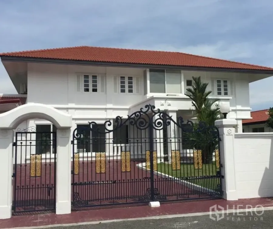 Detached House for rent in Bang Phli, Samut Prakan - Two-storey white detached house with red tile roof and ornate wrought-iron gate.