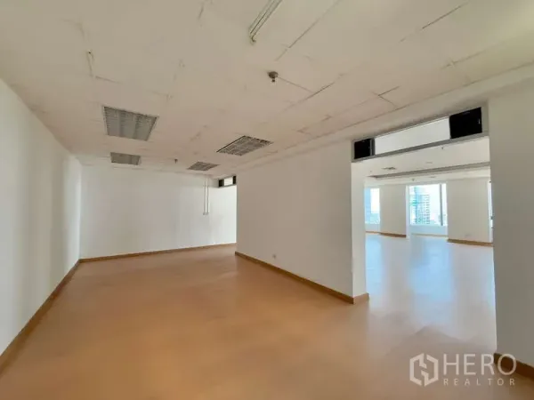 Office Space for rent in Chatuchak, Bangkok - Open corridor linking two office zones with drop ceiling lights and laminate flooring.