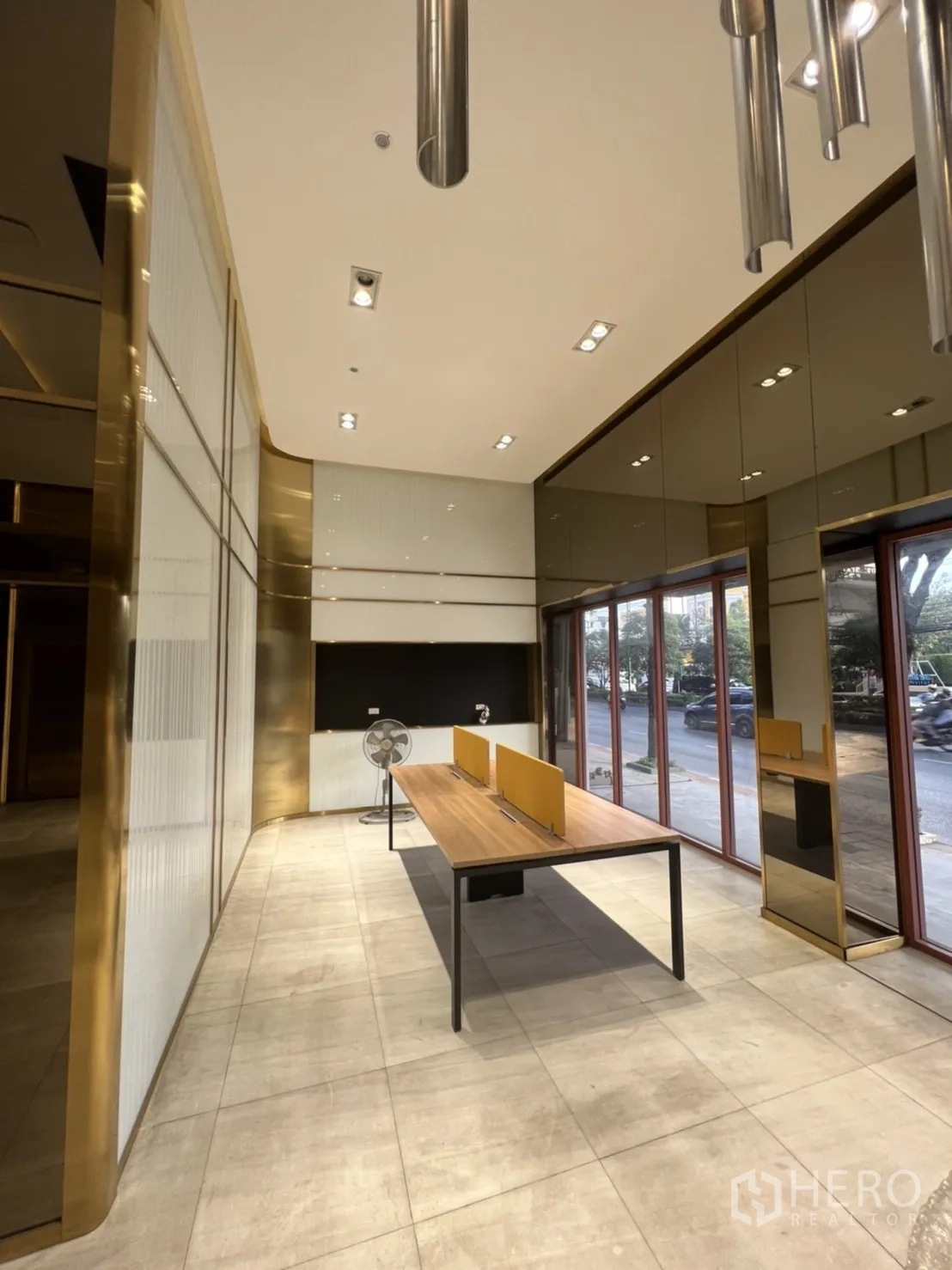 Shophouse for rent in Phra Khanong, Bangkok - Ground‑floor retail space with large street‑facing windows, tiled floor and long worktable under spotlights.