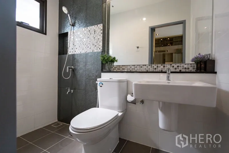 Townhouse for rent in Bang Phli, Samut Prakan - Bright bathroom with a window, textured-tile walk-in shower and a wide vanity mirror.