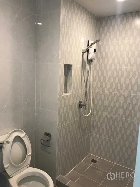 Townhouse for rent or sale in Prawet, Bangkok - Tiled bathroom featuring a walk-in shower with water heater and toilet.