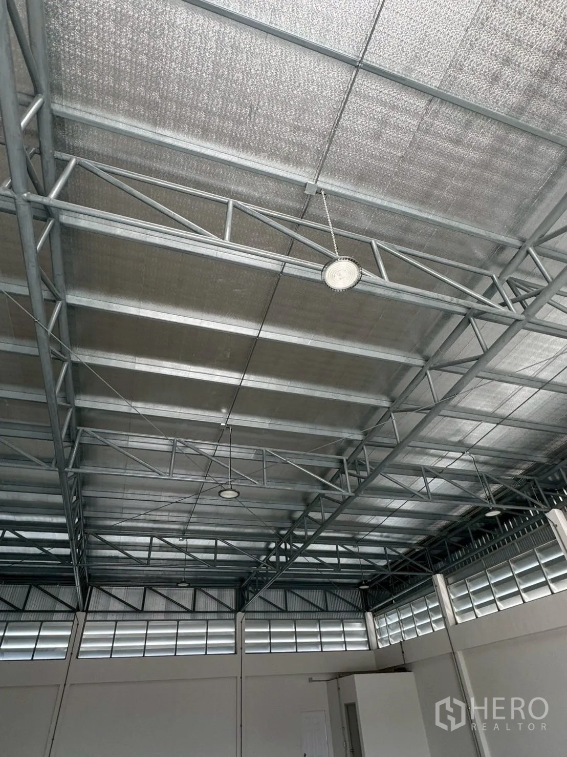 Warehouse for rent or sale in Nong Chok, Bangkok - Detail of metal truss structure and insulated roofing with hanging circular LED lights.