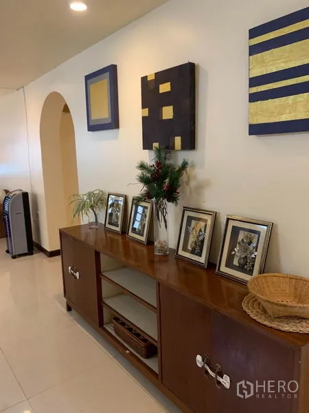 Townhouse for rent or sale in Phra Khanong, Bangkok - Hallway featuring a mid-century cabinet, recessed lighting and decorative artwork.