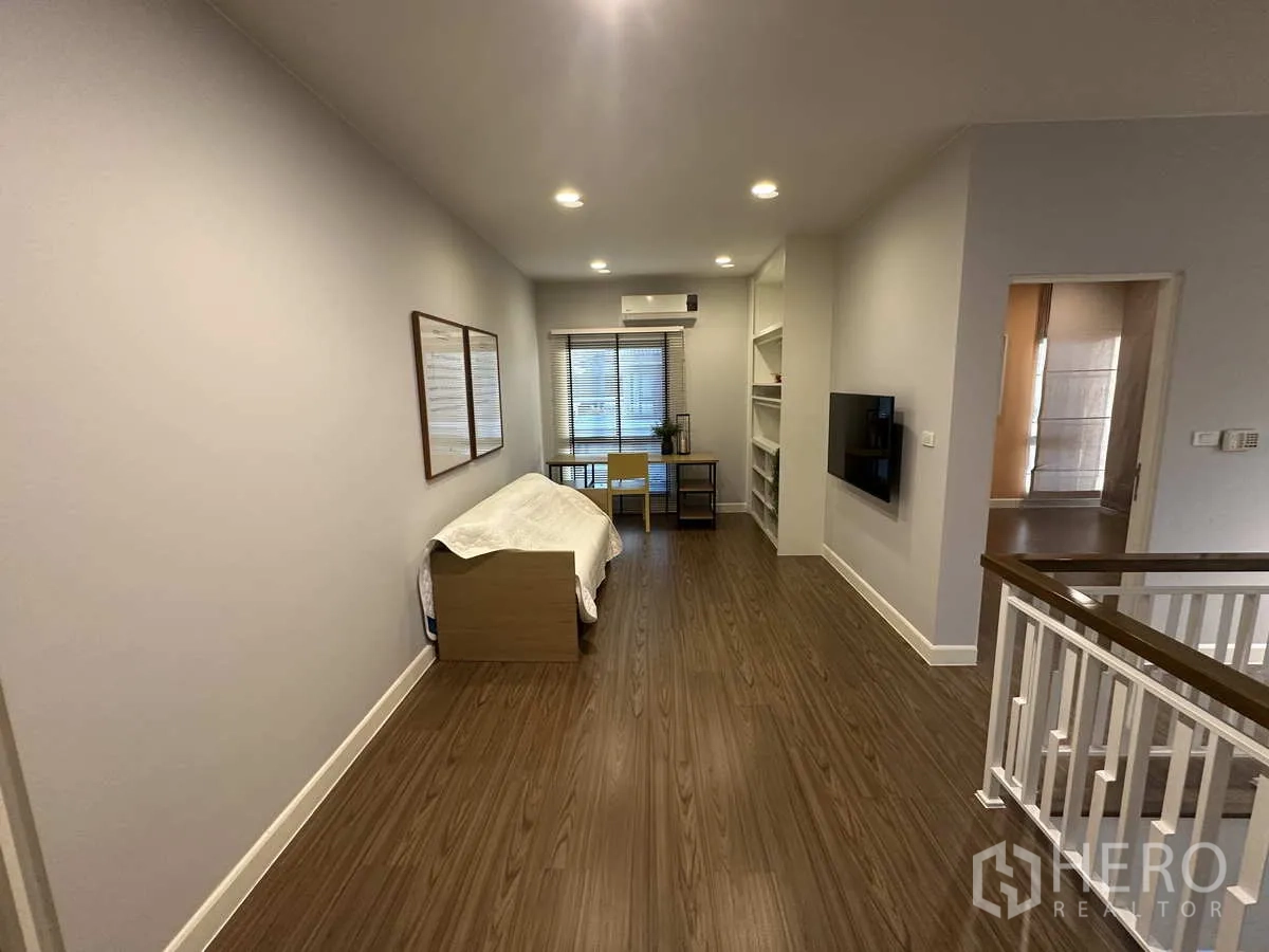 Detached House for rent or sale in Lam Luk Ka, Pathum Thani - Upstairs family area or study nook with shelving and TV near staircase.
