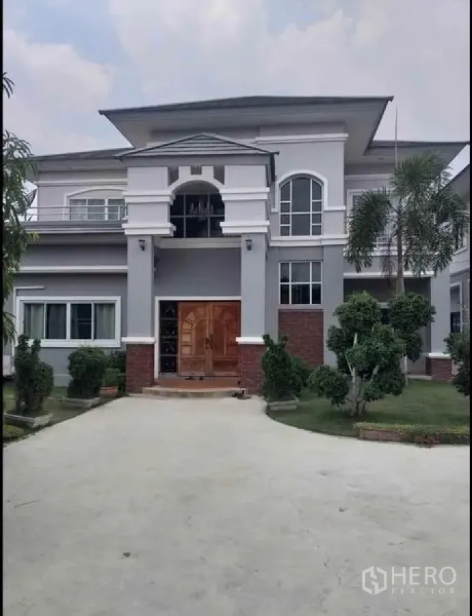 Detached House for sale in Lam Luk Ka, Pathum Thani - Front façade of the main two-storey house with arched windows and a wooden door.