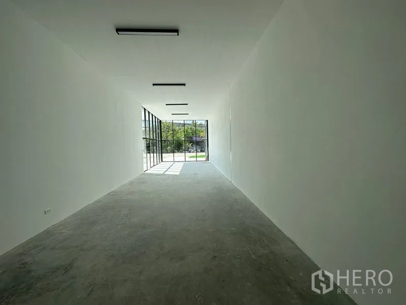 Warehouse for rent in Bang Phli, Samut Prakan - Long white showroom space facing the street through tall glass windows for display.