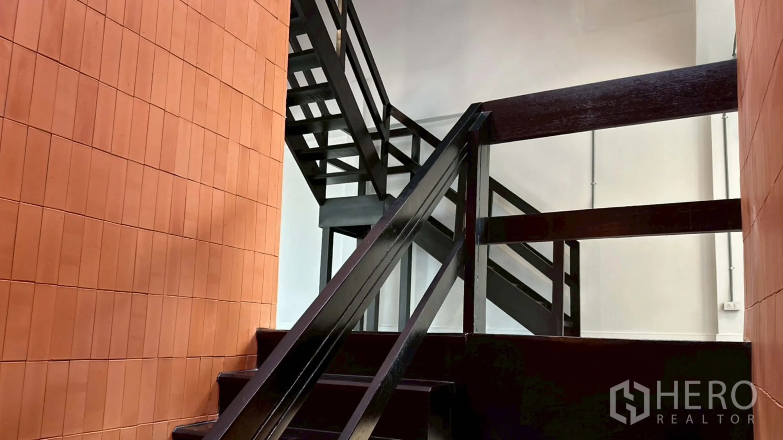 带办公室的家 出租在Watthana, Bangkok - 黑色金属楼梯结构与红陶墙面的近景。