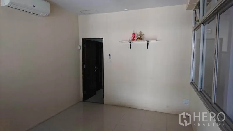 Warehouse for rent in Lak Si, Bangkok - Compact air-conditioned office room with tiled flooring and a wall shelf.