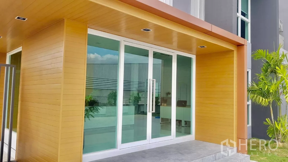 Warehouse for sale in Lam Luk Ka, Pathum Thani - Main glass sliding entrance under a wood-tone canopy.