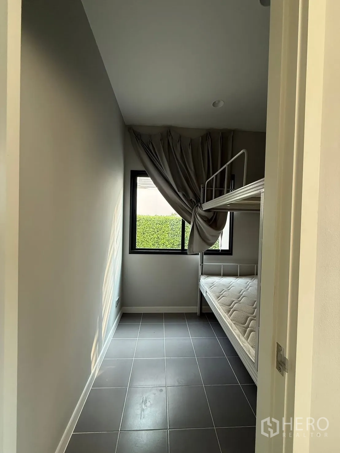 Detached House for rent in Bang Kapi, Bangkok - Compact room with a bunk bed, tiled floor and a window with drapes.