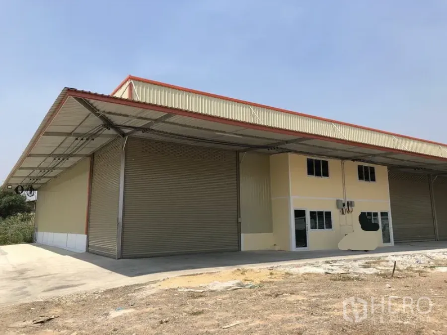 工厂 出租在Khlong Luang, Pathum Thani - 仓库正立面，带雨棚装卸区、卷闸门及两层办公室。