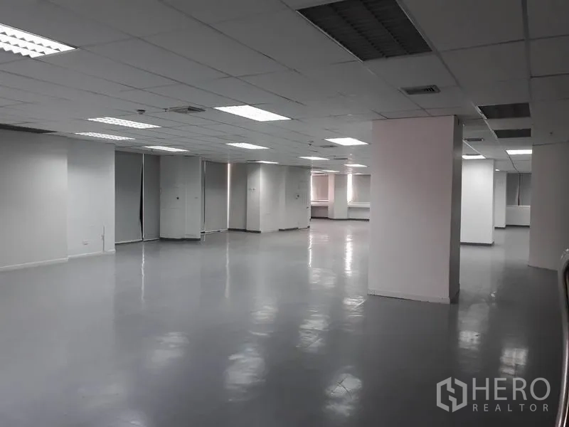 Office Space for rent in Huai Khwang, Bangkok - Wide work area with structural columns, bright fluorescent lighting and white walls