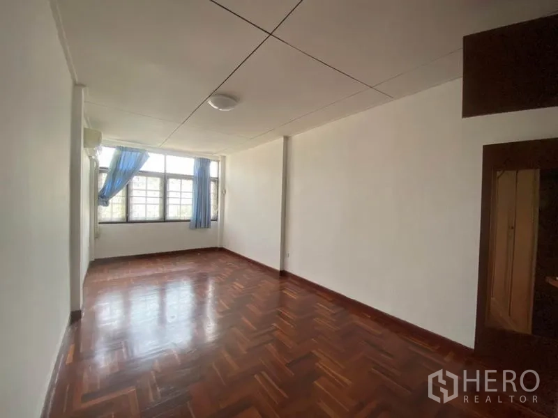Townhouse for rent in Watthana, Bangkok - Sunlit bedroom with large windows, blue curtains and parquet floors.