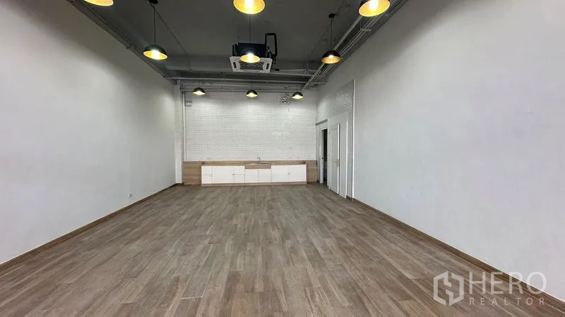 Retail Space for rent - Open-plan retail interior with wood floors, white brick feature wall and built-in cabinets.